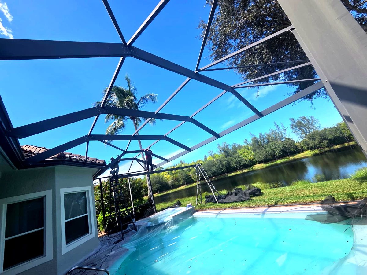 ABC Pool Cage Painting crew installing a pool cage screen enclosure frame in Florida