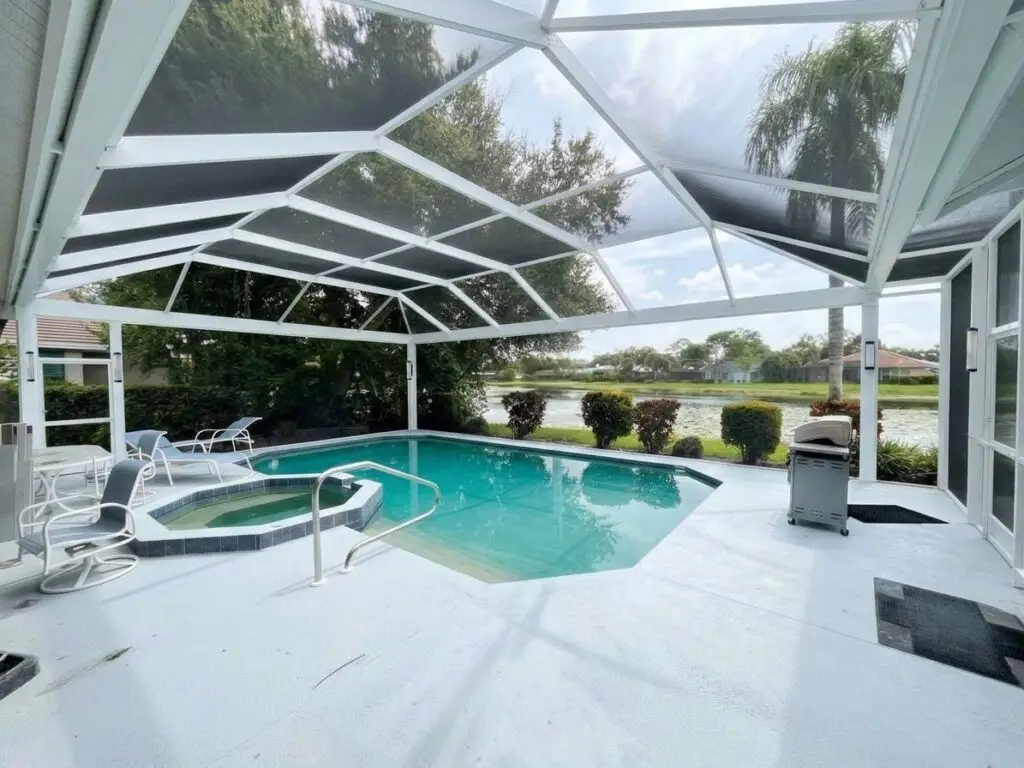 White pool cage over the pool and spa after a panoramic picture-window screen conversion, with a clear view of the backyard
