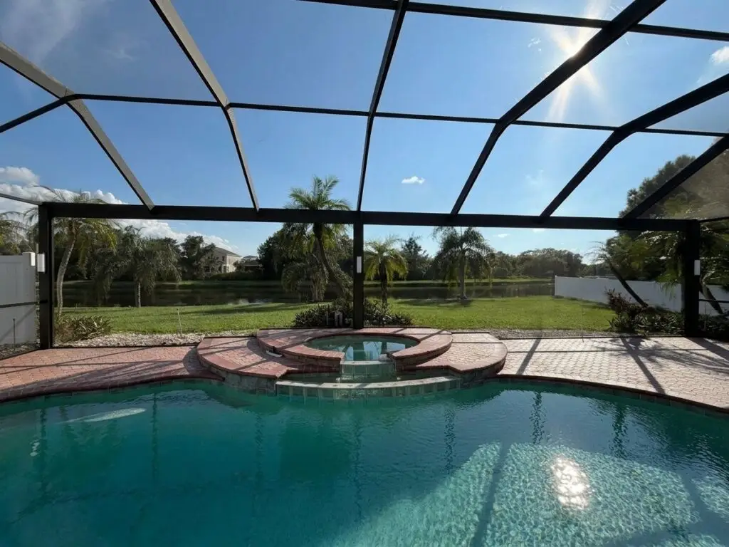 Black pool cage over the pool after a panoramic picture-window screen conversion, with a clear golf-course view
