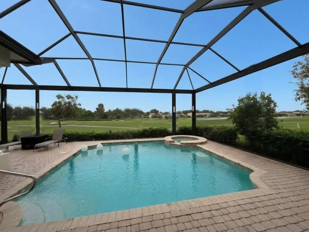 Black pool cage over the pool after a panoramic picture-window screen conversion, with a clear lake view