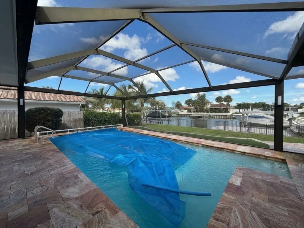 Black pool cage over the pool after a panoramic picture-window screen conversion, with an open waterfront view