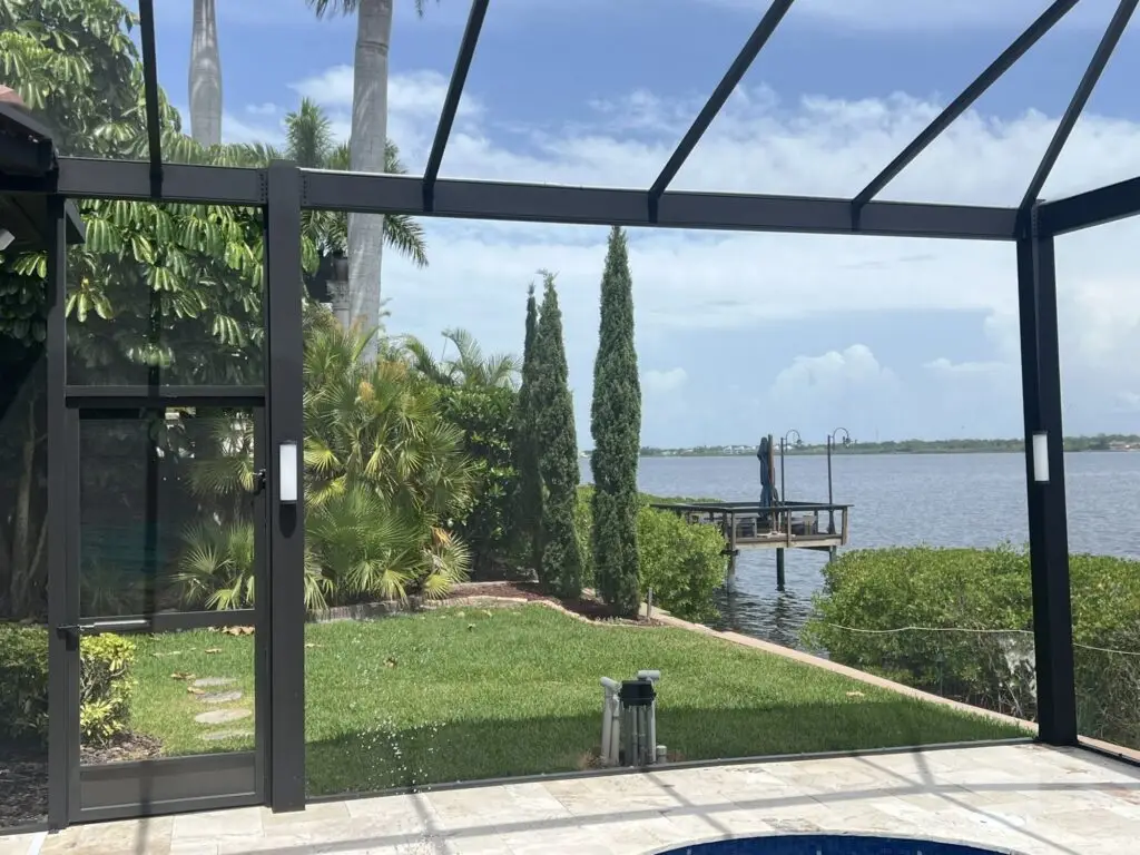 Pool cage by the water with LED column lights installed on the posts, seen in daylight