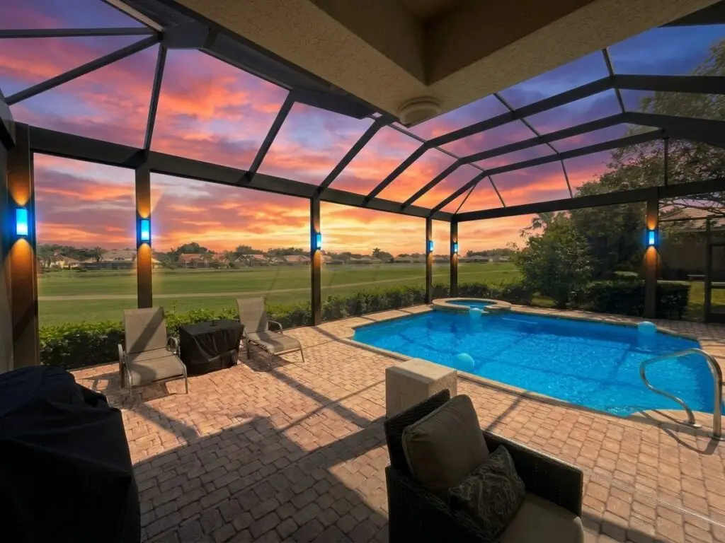 Pool cage LED column lights glowing at sunset over a golf-course view