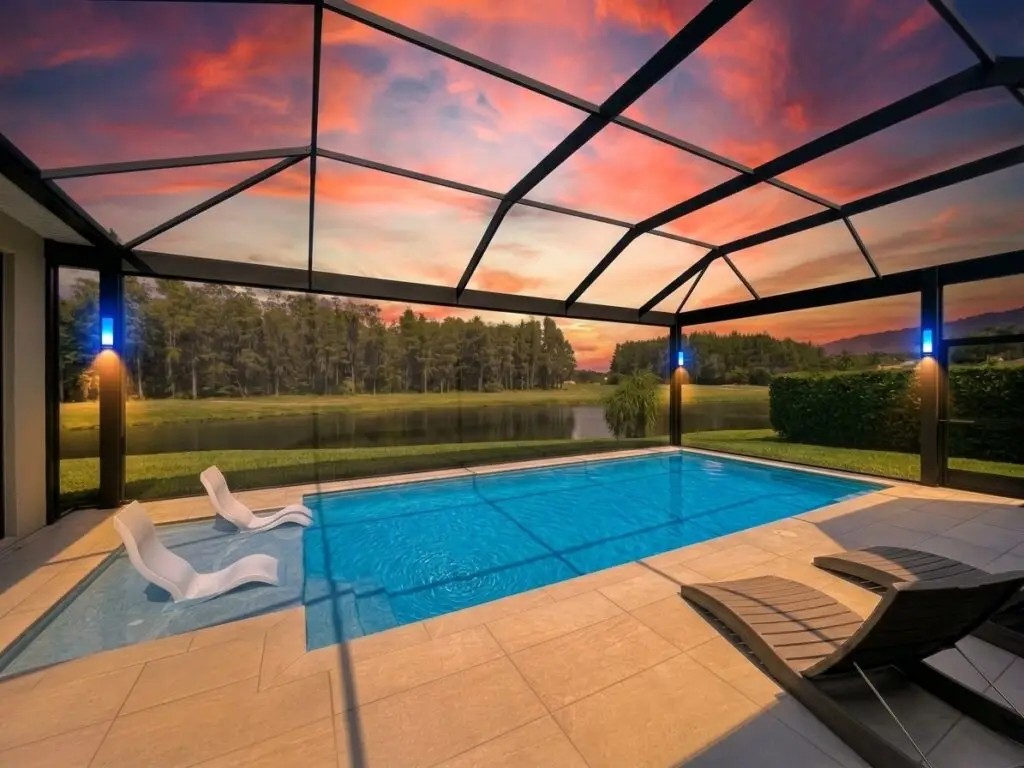 Pool cage LED post lights at sunset around a lap pool with a preserve view