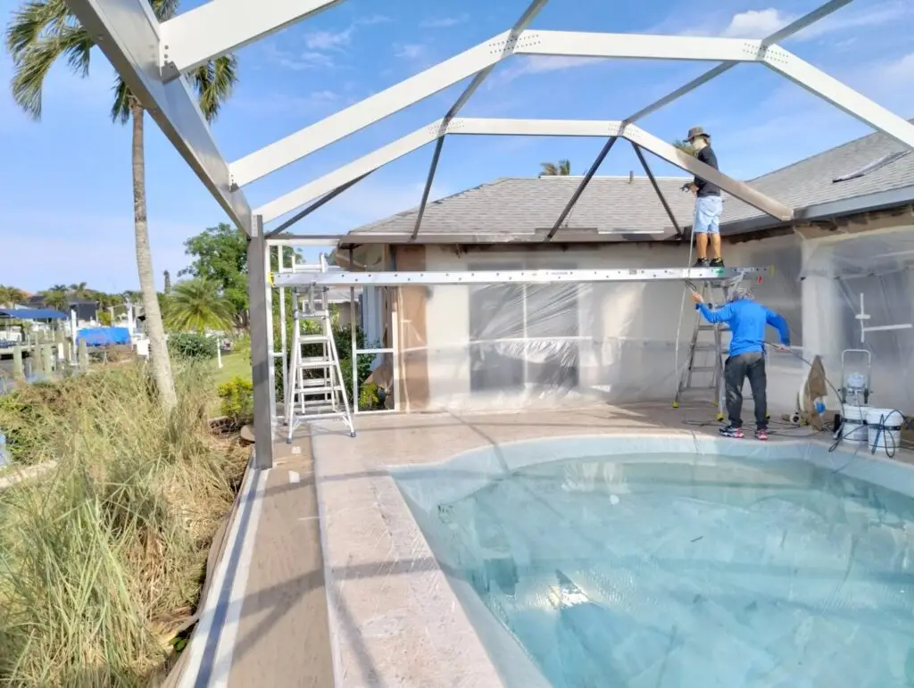 Crew painting and rescreening a white pool cage over the pool
