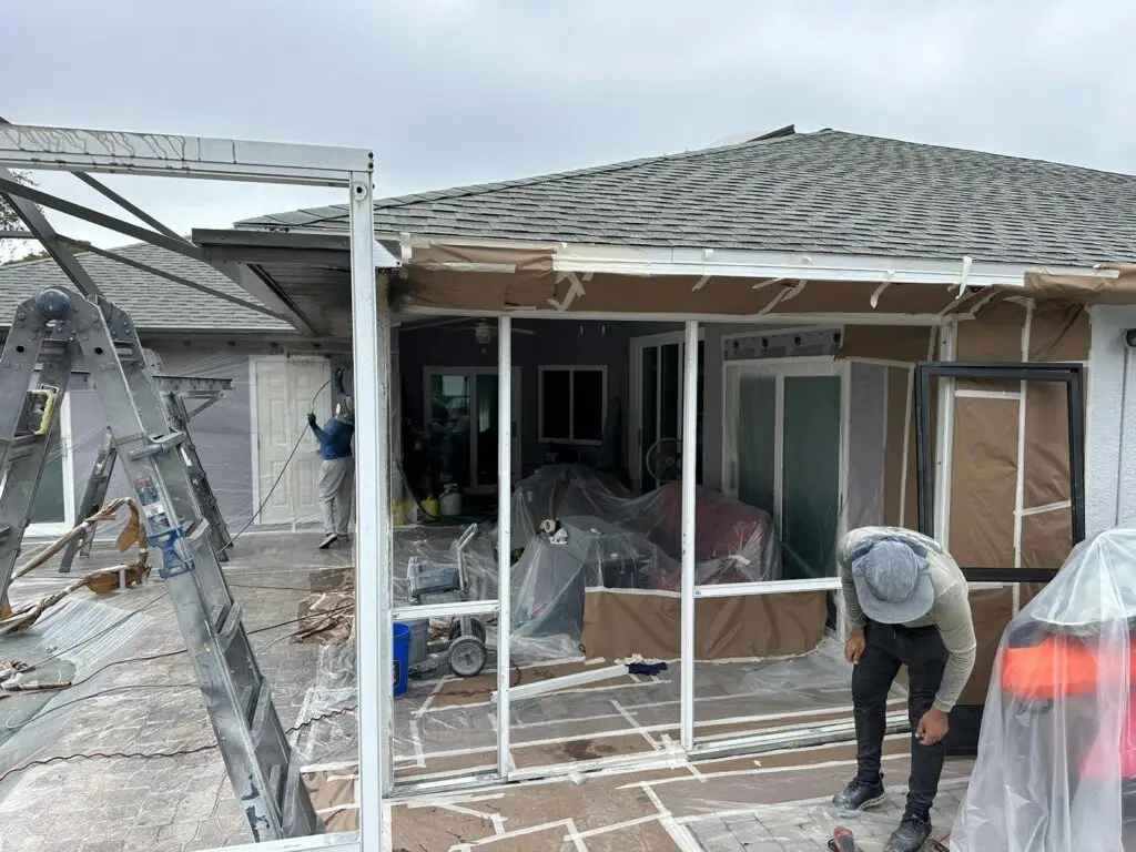 Lanai screen enclosure masked with plastic while the white frame is painted