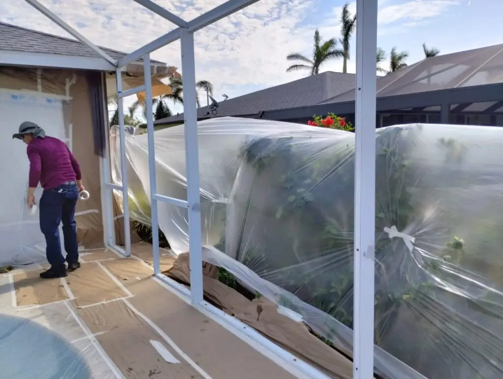 Pool lanai frame painted white, with the plants covered in plastic for protection