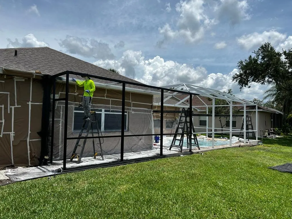 Crew rescreening a bronze pool cage, new screen panels going in