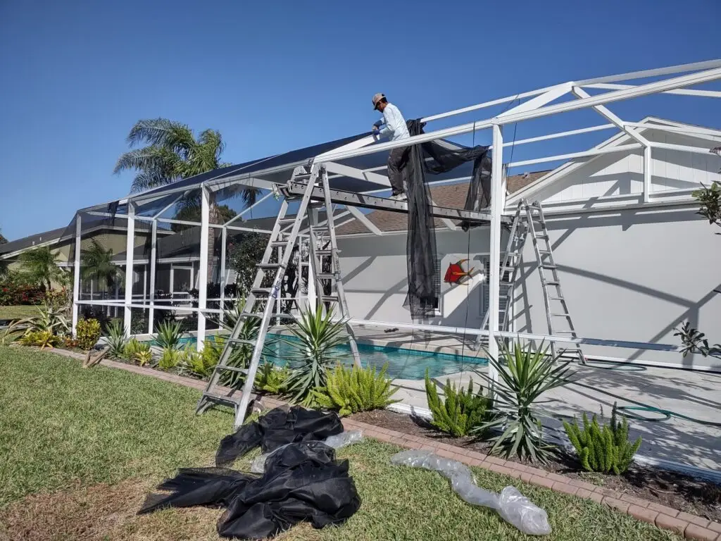 Crew rescreening a white pool cage, new mesh over the roof panels