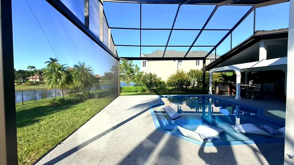 Freshly painted black pool cage enclosure over a pool and spa in Florida by ABC Pool Cage Painting